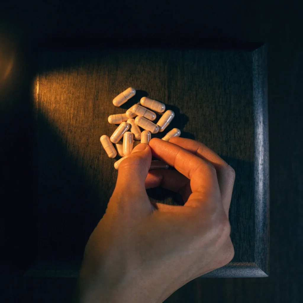 A matte white joint-mobility capsule beside an amber-tinted one on folded brown paper towel under a warm pooled light